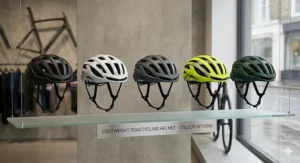 A display of identical lightweight road cycling helmets, showing colour options including matte black, gloss white, grey, fluorescent yellow, and British racing green on minimalist shelves within a contemporary London cycling shop.