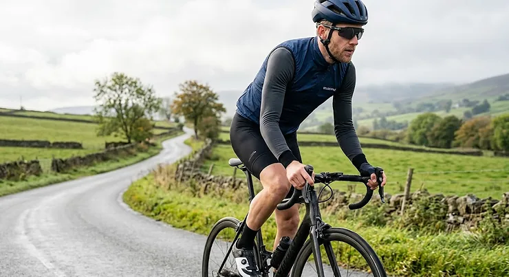 Cyclist wearing a men's navy blue windproof cycling gilet over a long sleeve jersey