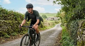 Illustration of a road cyclist wearing a merino cycling base layer whilst riding along a British country lane