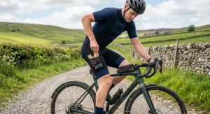 A gravel cyclist using the mesh side cargo pocket on a pair of adventure-ready men's bib shorts to store snacks.