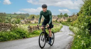 Cyclist in a dark green lightweight long sleeve cycling jersey designed for changeable British spring weather conditions.