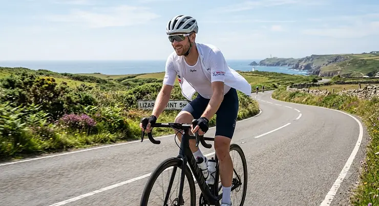 Cyclist wearing a lightweight white sleeveless mesh summer cycling base layer underneath an unzipped jersey on a sunny ride.