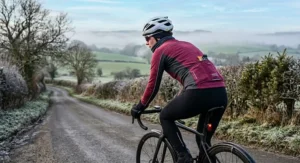 A female cyclist wearing a long sleeve thermal women's cycling jersey designed for cold winter road riding in the UK.