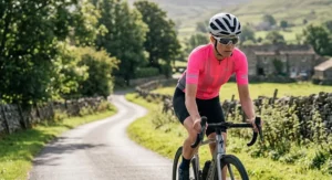 A woman cyclist in a high-visibility pink short sleeve cycling jersey with breathable mesh side panels.