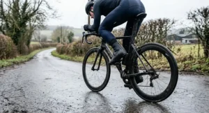 Cyclist wearing sleek aerodynamic neoprene overshoes during a chilly time trial on a British country road.