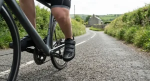 Cyclist wearing beginner-friendly budget road shoes clipped into road bike pedals on a British country lane