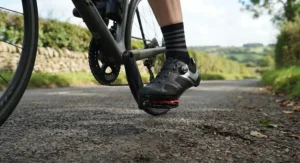 Cyclist clipping into road pedals while wearing professional clipless road cycling shoes on a British country lane.