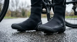 Pair of neoprene thermal waterproof cycling overshoes fitted over road cycling shoes on a wet asphalt surface