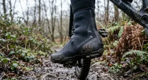 Thick 5mm deep-winter neoprene overshoes splashed with mud during off-road mountain biking on British trails.